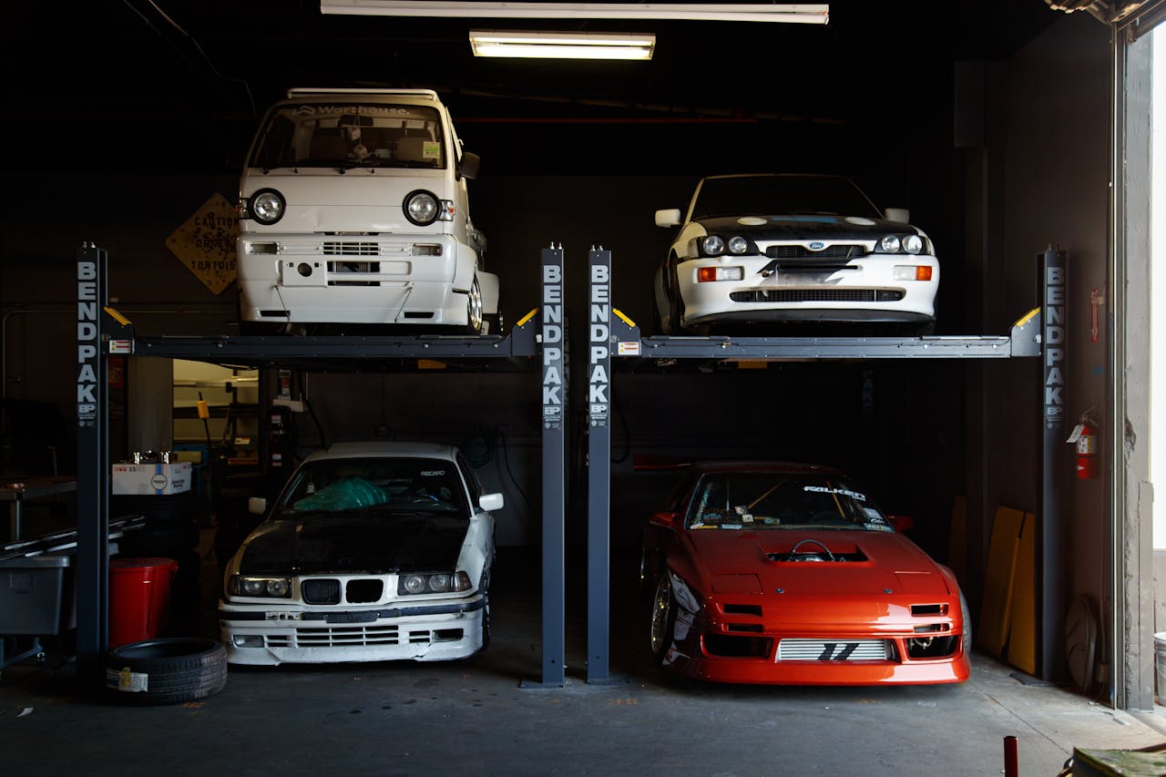 A collection of modified sports cars on a mechanical garage lift in Compton, CA.