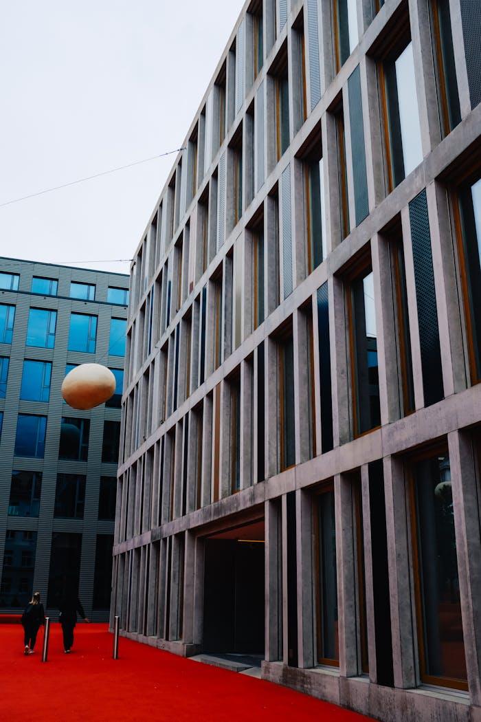 Vertical shot of a modern urban bank building with striking architecture and a red carpet pathway.