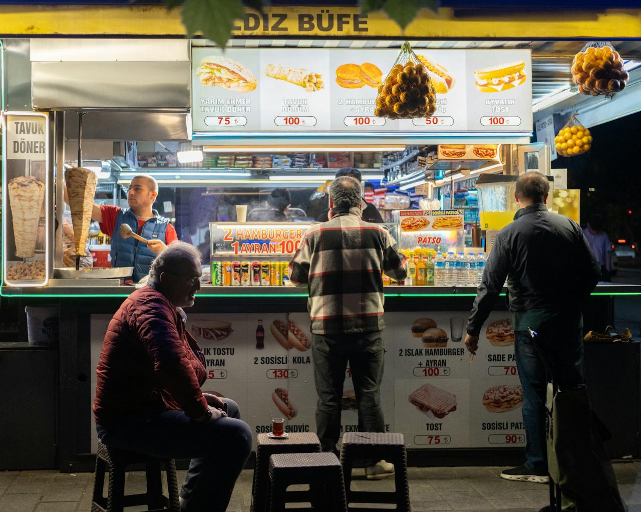 Lively street food stand in İstanbul at night, serving variety of snacks.