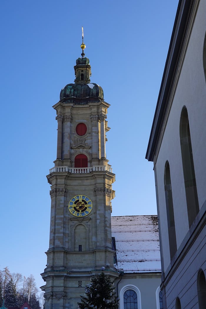 Historic St. Gallen Abbey tower with clock, captured under a bright blue sky.
