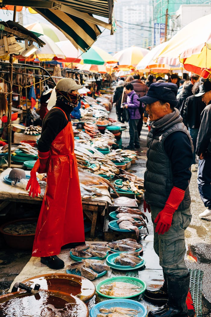 Colorful fish market in Busan bustling with vendors and fresh seafood under bright umbrellas.