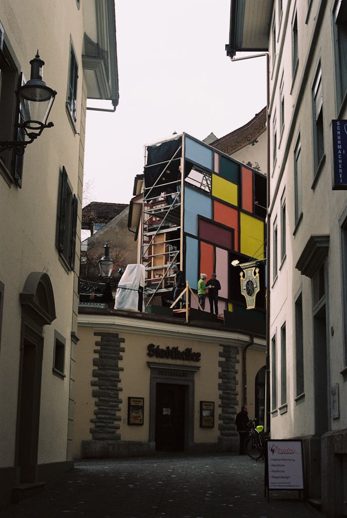 Colorful artwork on building facade in a Swiss alleyway.