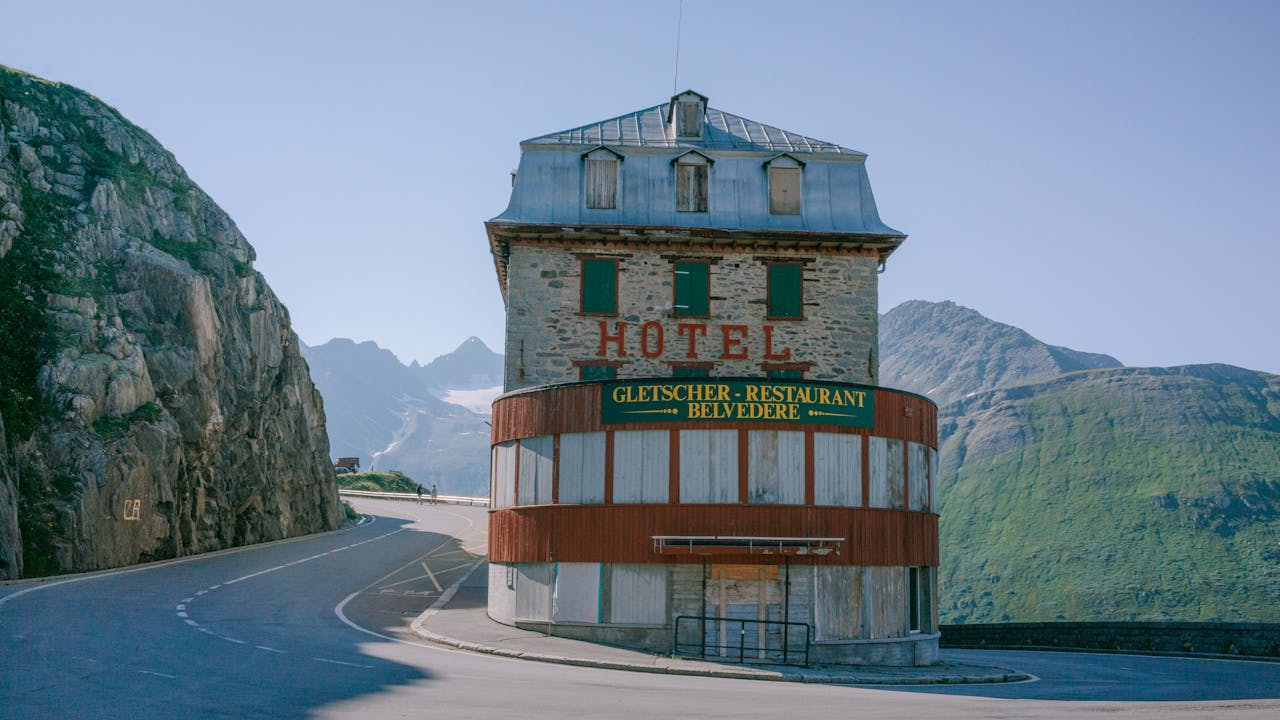A scenic view of Hotel Belvedere nestled on a mountain road in Obergoms, Switzerland.